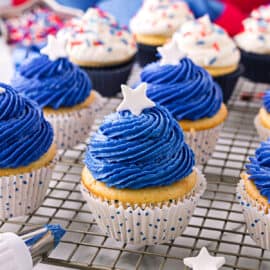 White cupcakes with blue frosting on a wire cooling rack.