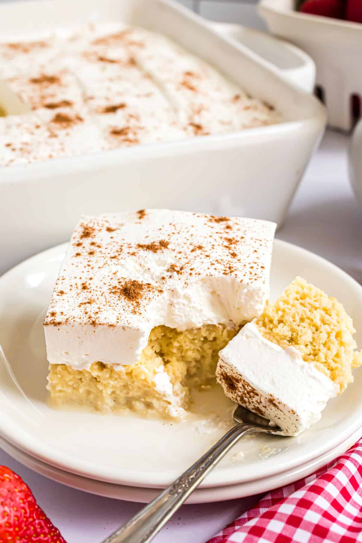 Tres leches cake with a fork taking a bite.
