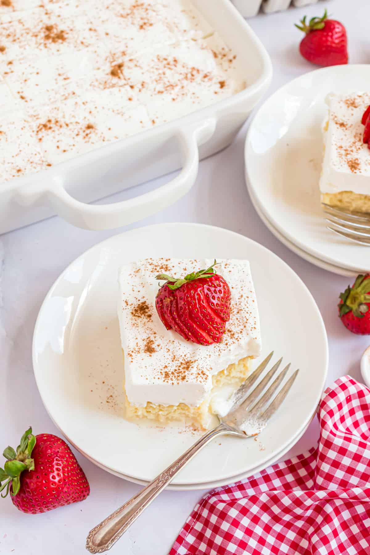 Two slices of tres leches cake served on white dessert plates.