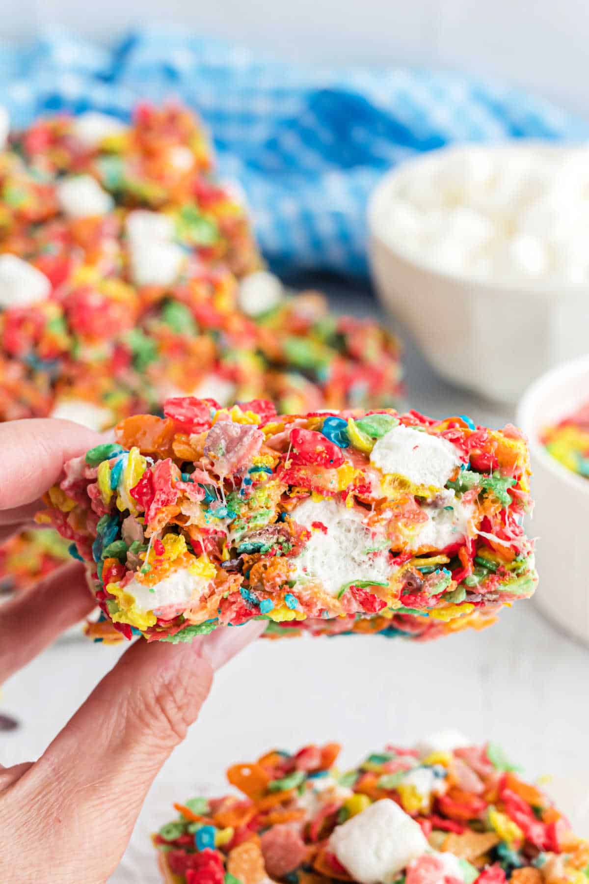 Fruity pebbles rice krispie treats being held before taking a bite.