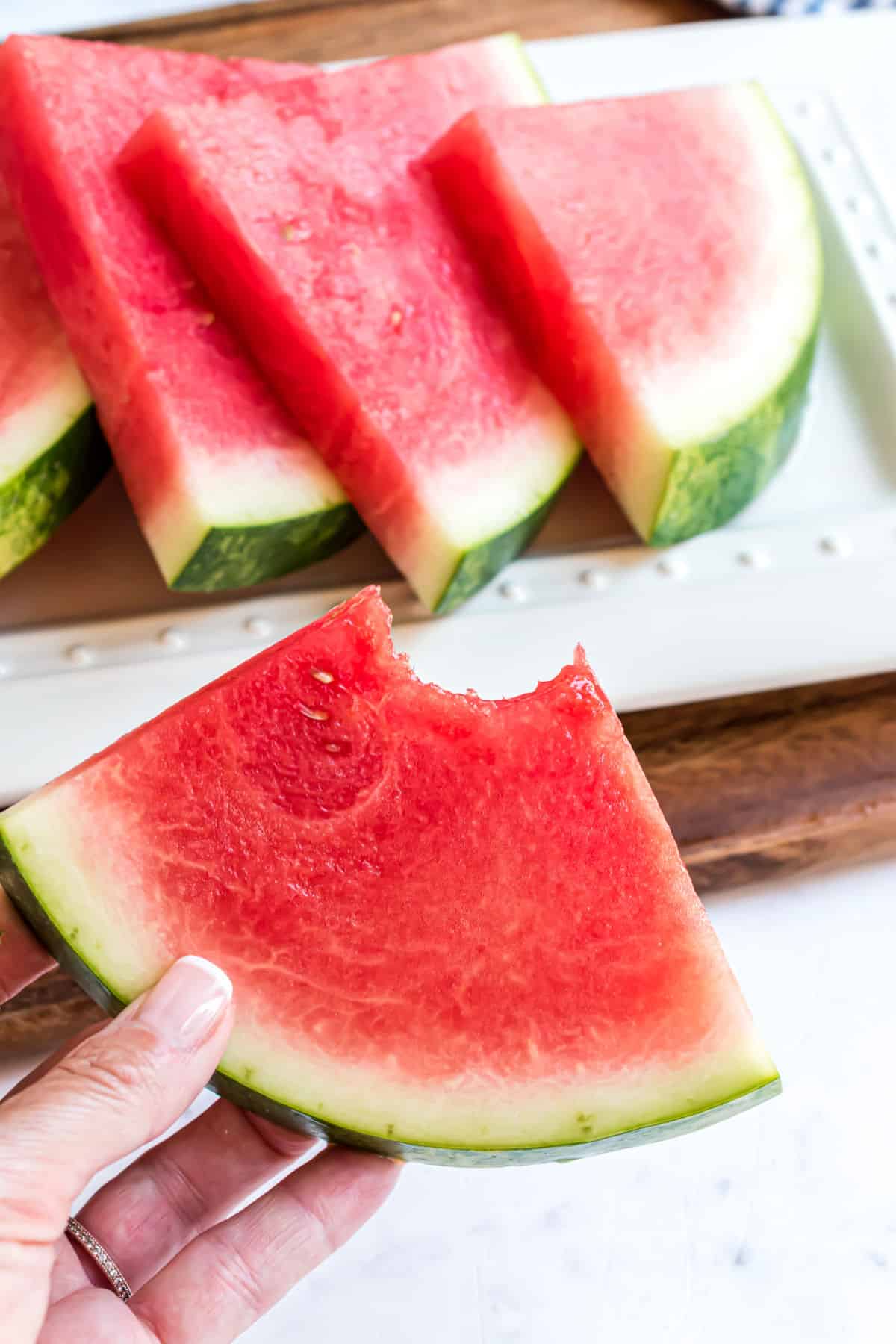 Wedge of watermelon with a bite taken out.