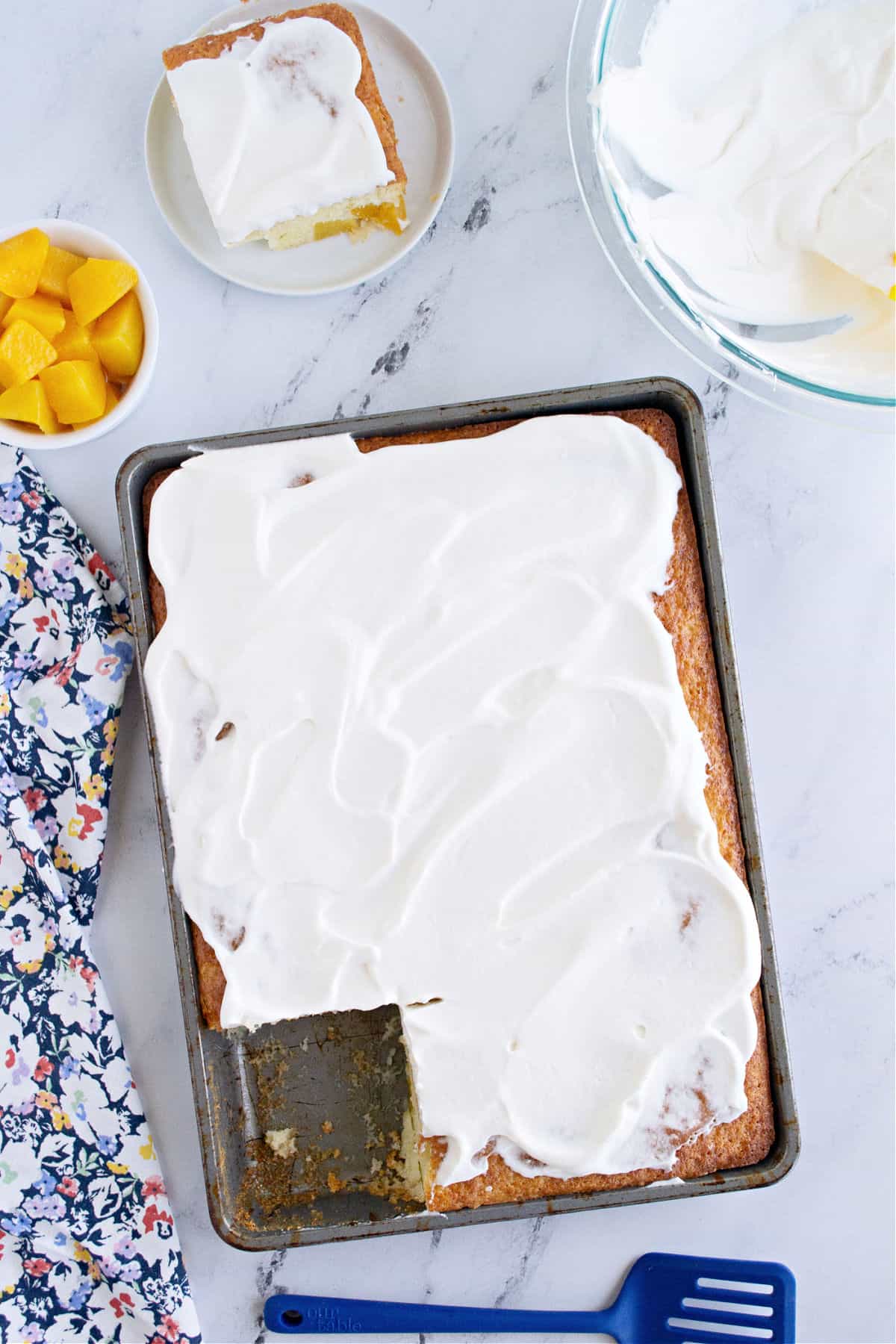 Peach cake topped with whipped cream in a 13x9 baking dish.