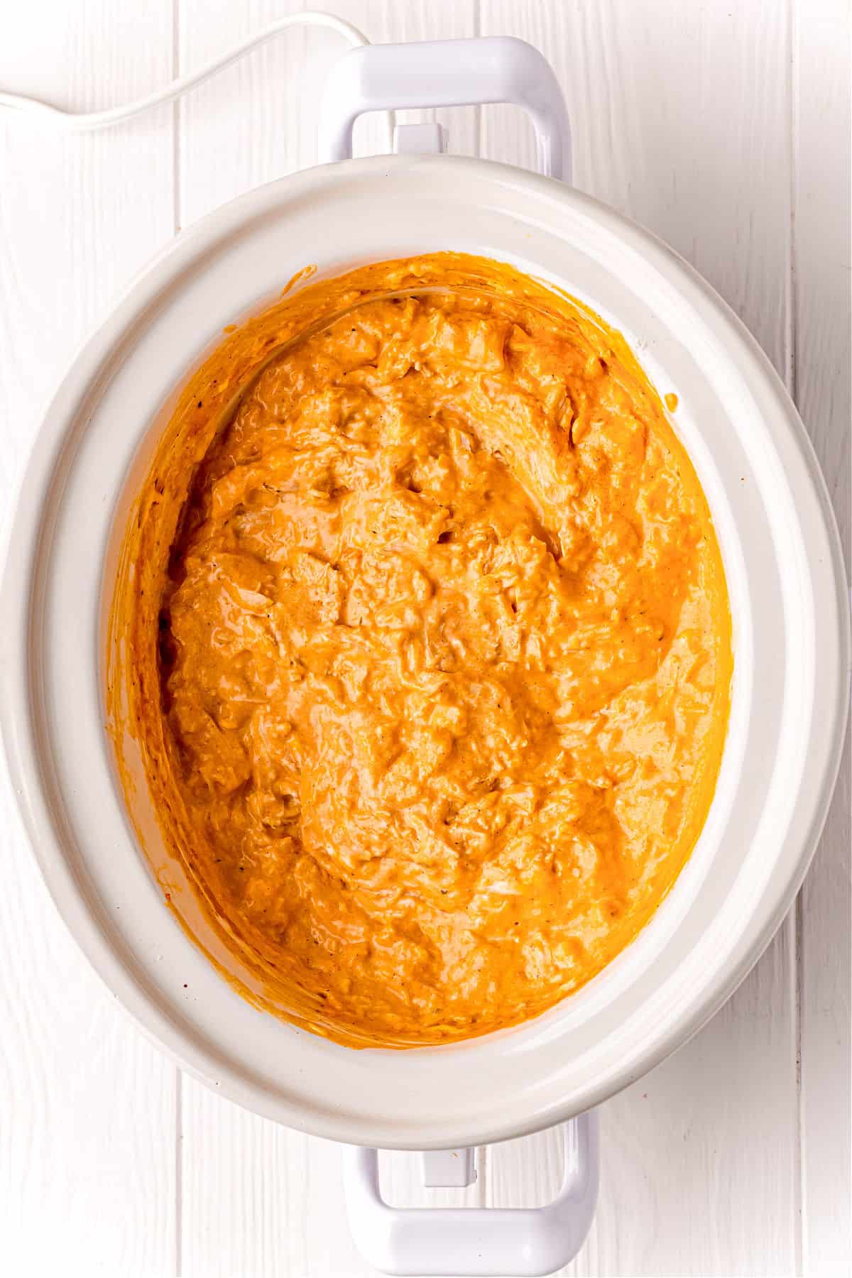 Buffalo chicken dip in a white slow cooker.