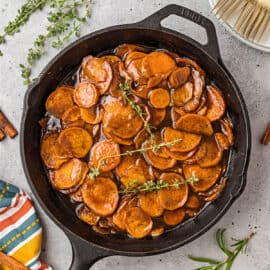 Candied sweet potatoes baked in a cast iron skillet with fresh thyme.