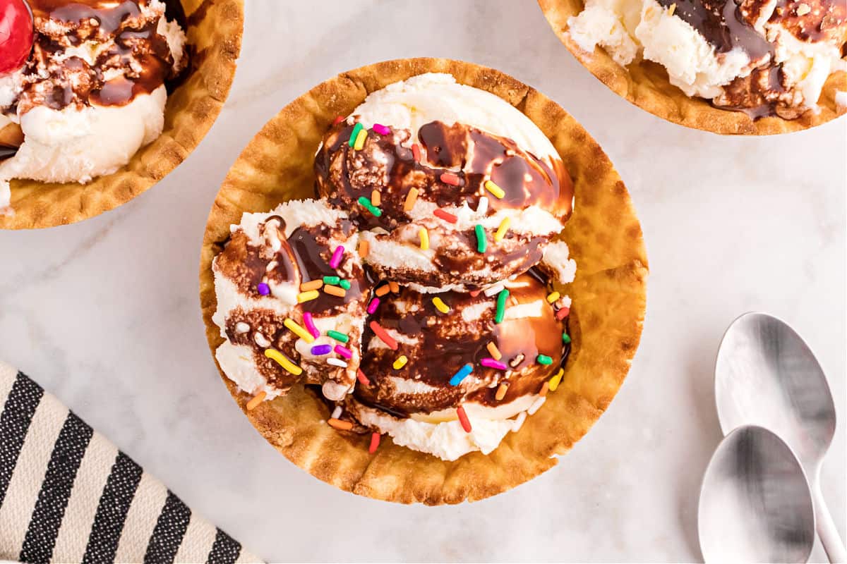 Chocolate syrup on vanilla ice cream in a waffle bowl with sprinkles.