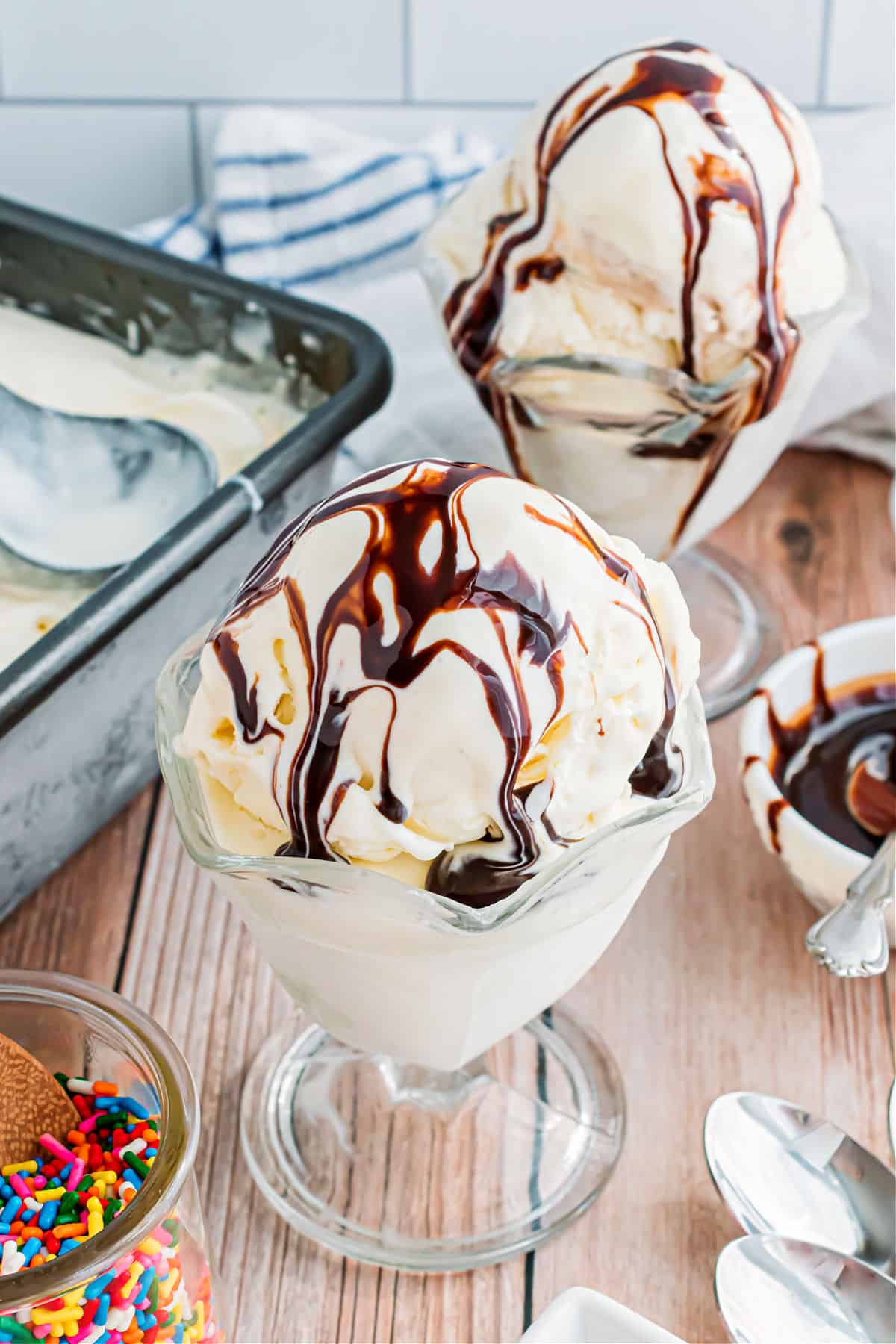 Two bowls of vanilla ice cream with chocolate syrup.