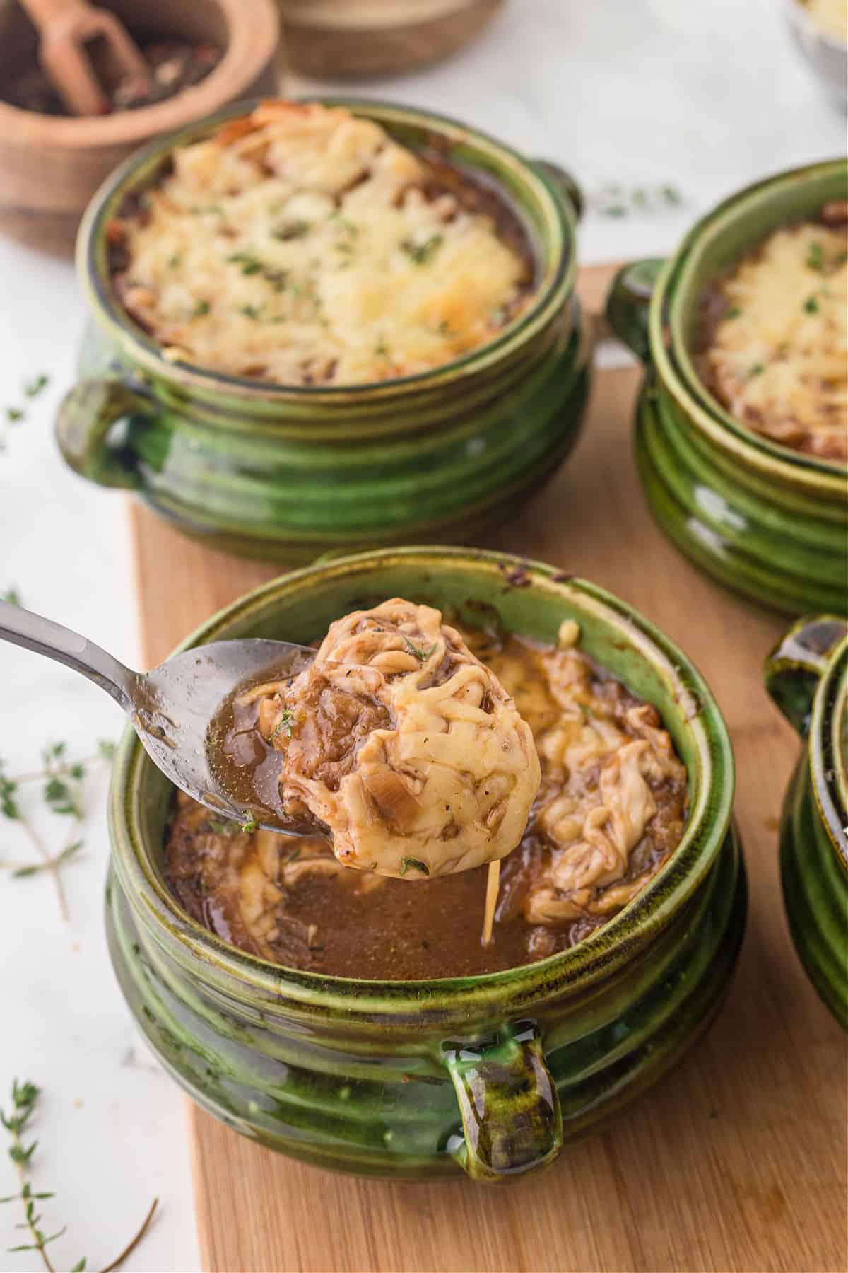 French onion soup in a green bowl with a spoon.