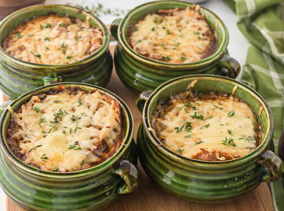 Four bowls of french onion soup with sourdough and swiss cheese on top.