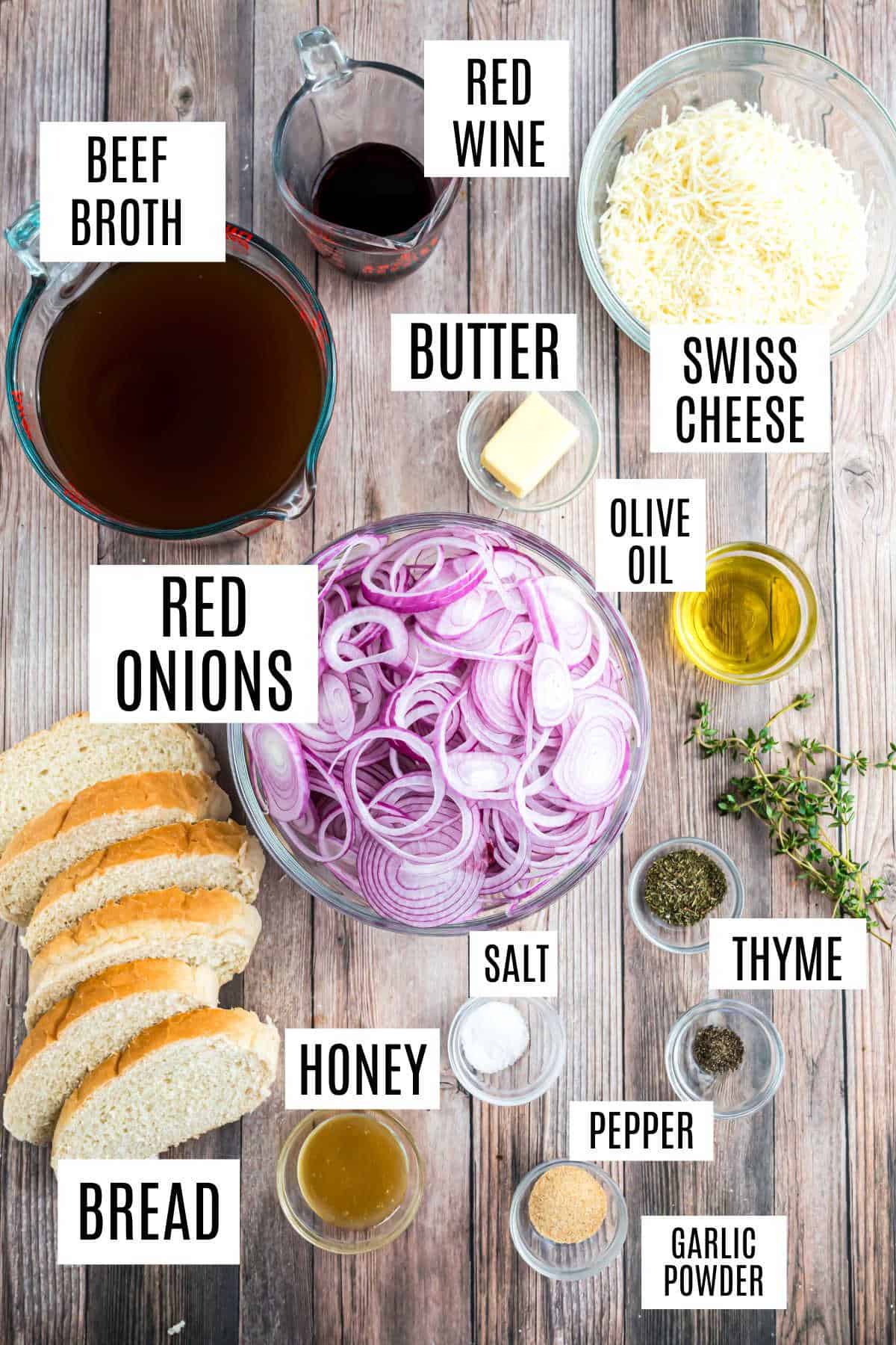 Top view of french onion soup ingredients: red onions, beef broth, red wine, Swiss cheese, bread, and seasonings.