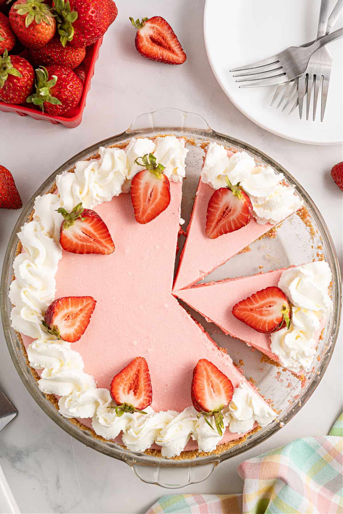 Strawberry jello pie sliced and topped with fresh strawberries and whipped cream.