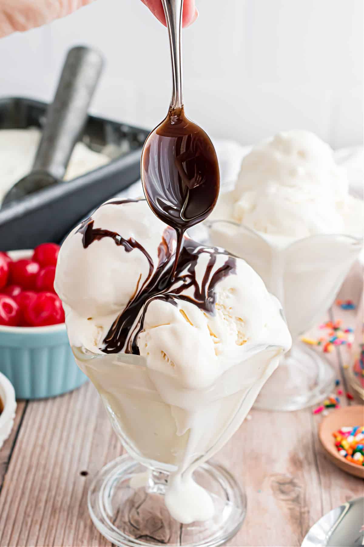 Chocolate syrup being drizzled over a dish of vanilla ice cream.