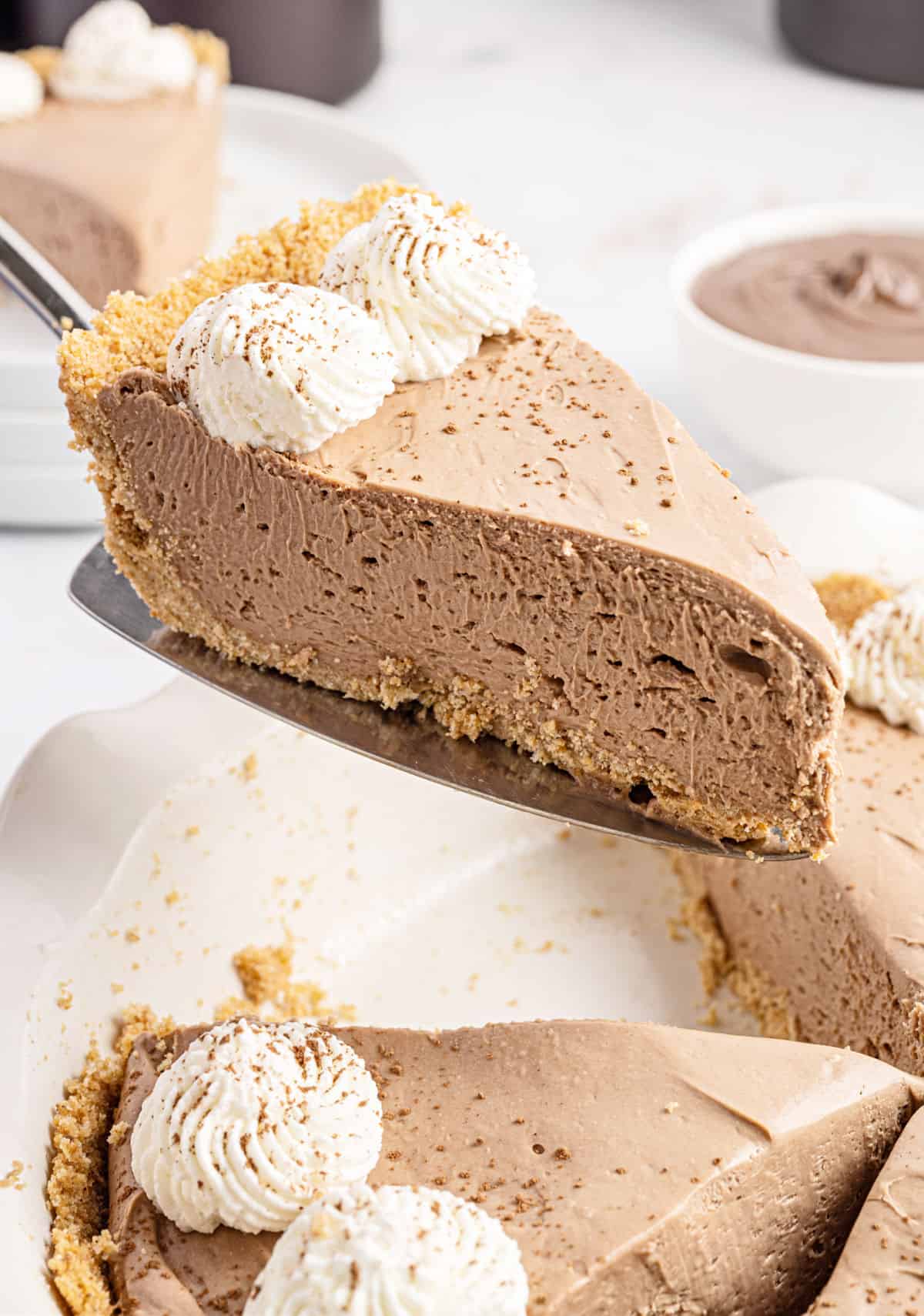 Slice of nutella cheesecake being lifted out of white pie plate.