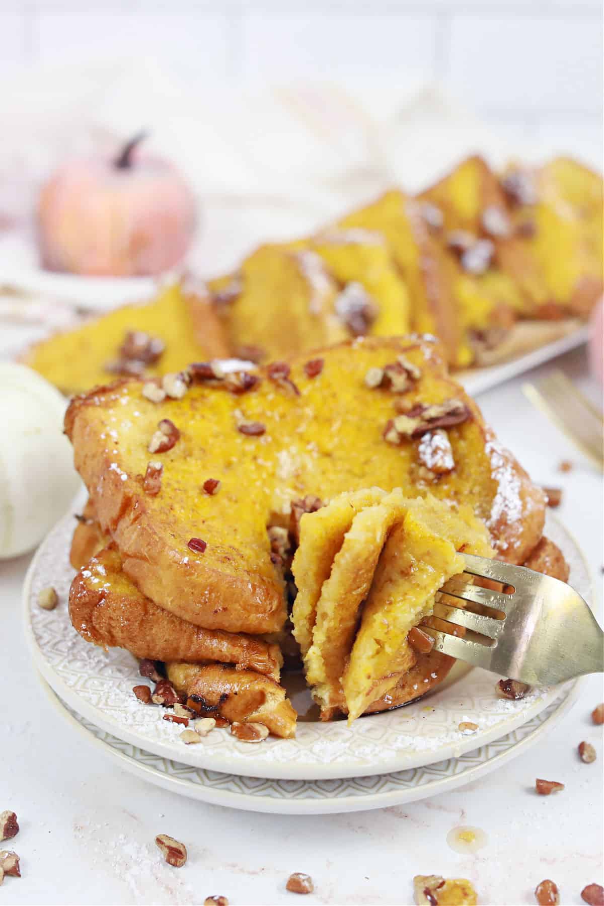 Stack of french toast with a bite being taken off plate.