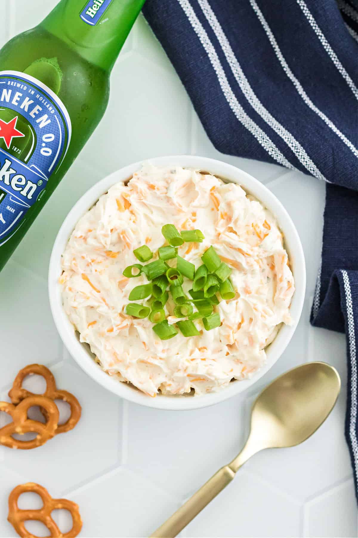 Cheese dip made with beer served in a white bowl with green onion garnish.