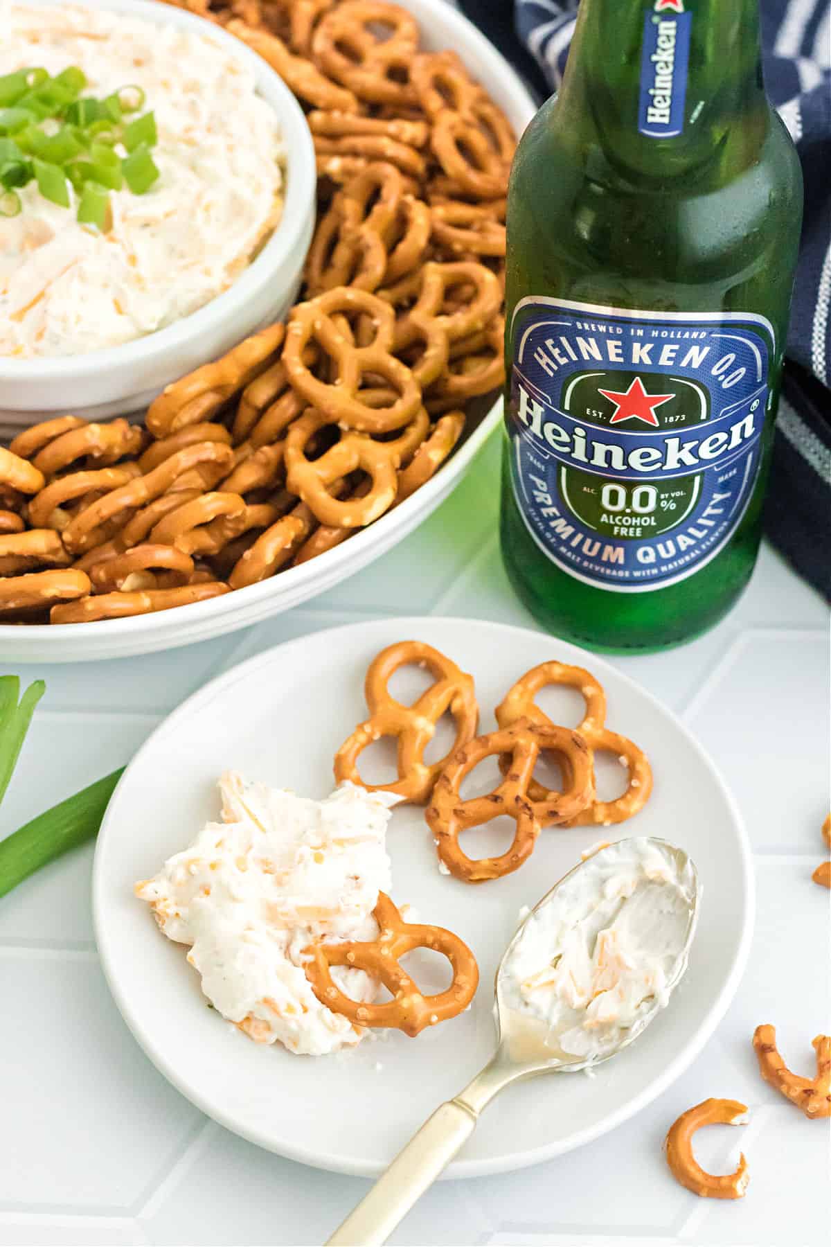 Beer cheese dip served on a white plate with pretzels and a beer.