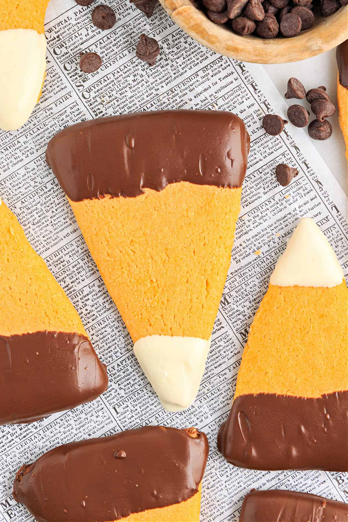 Sugar cookies shaped like candy corn with melted chocolate.