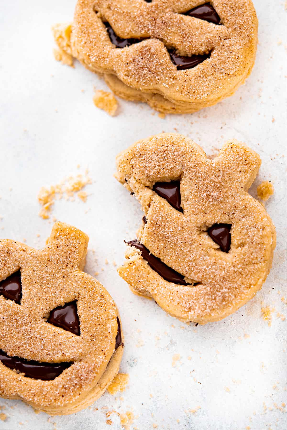 Pumpkin sandwich cookies with a bite taken out.