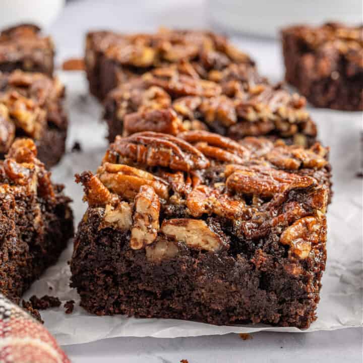 I brownies alla torta di noci pecan hanno una base di brownie densa e fondente condita con una topping di torta di noci pecan sciropposa zuccherata per un delizioso mash-up di dessert!