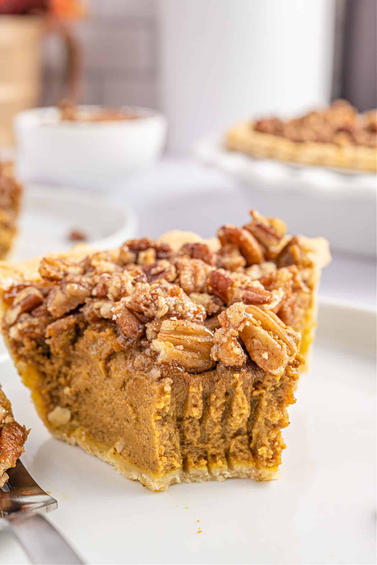 Slice of pumpkin pecan pie with a bite removed.