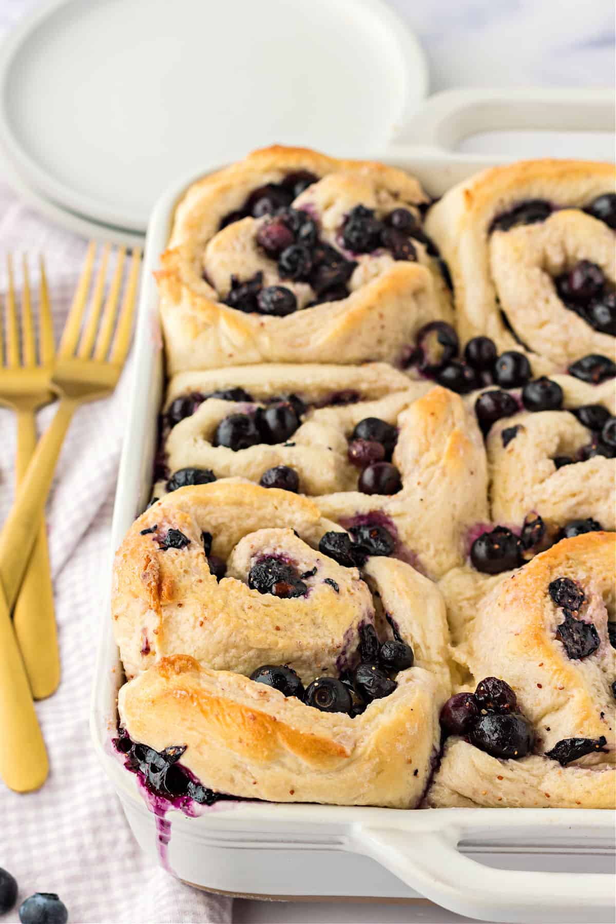 Unfrosted blueberry rolls baked in a baking dish.