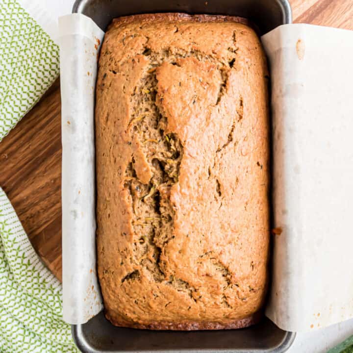 Zucchini bread in a loaf pan with parchment paper.