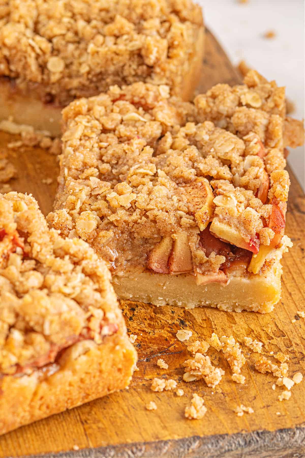 Apple pie bars cut into squares on a wooden cutting board.
