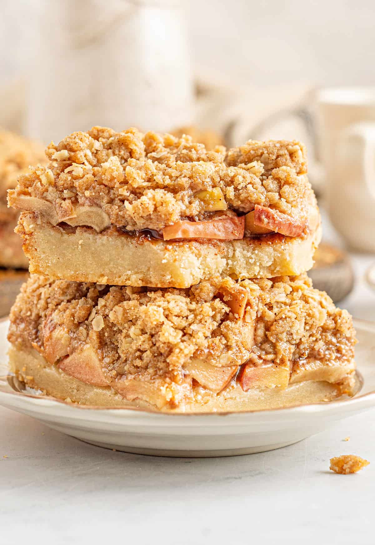 Stack of two apple pie bars on a white plate.