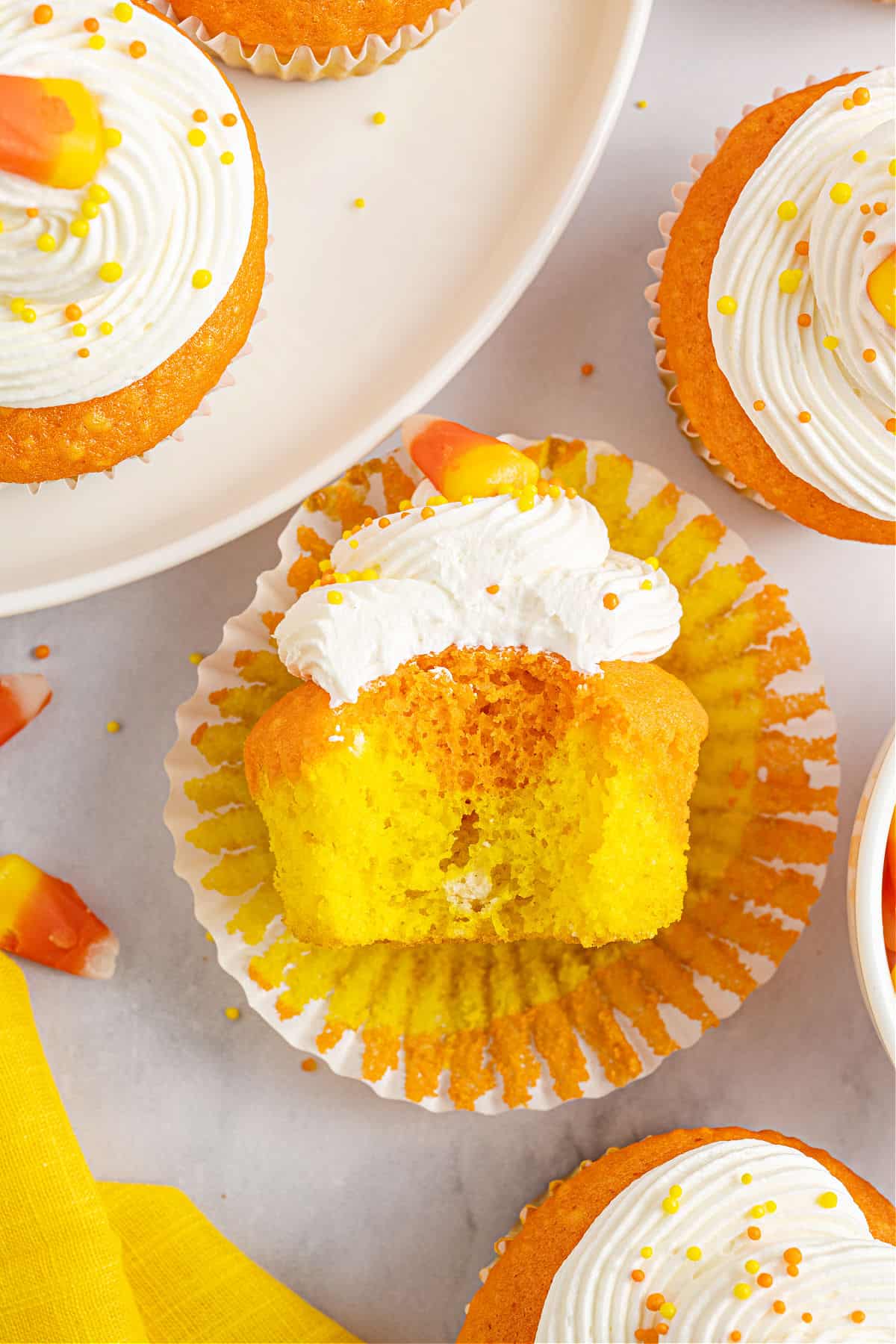 Yellow and orange cupcake with a bite taken out.