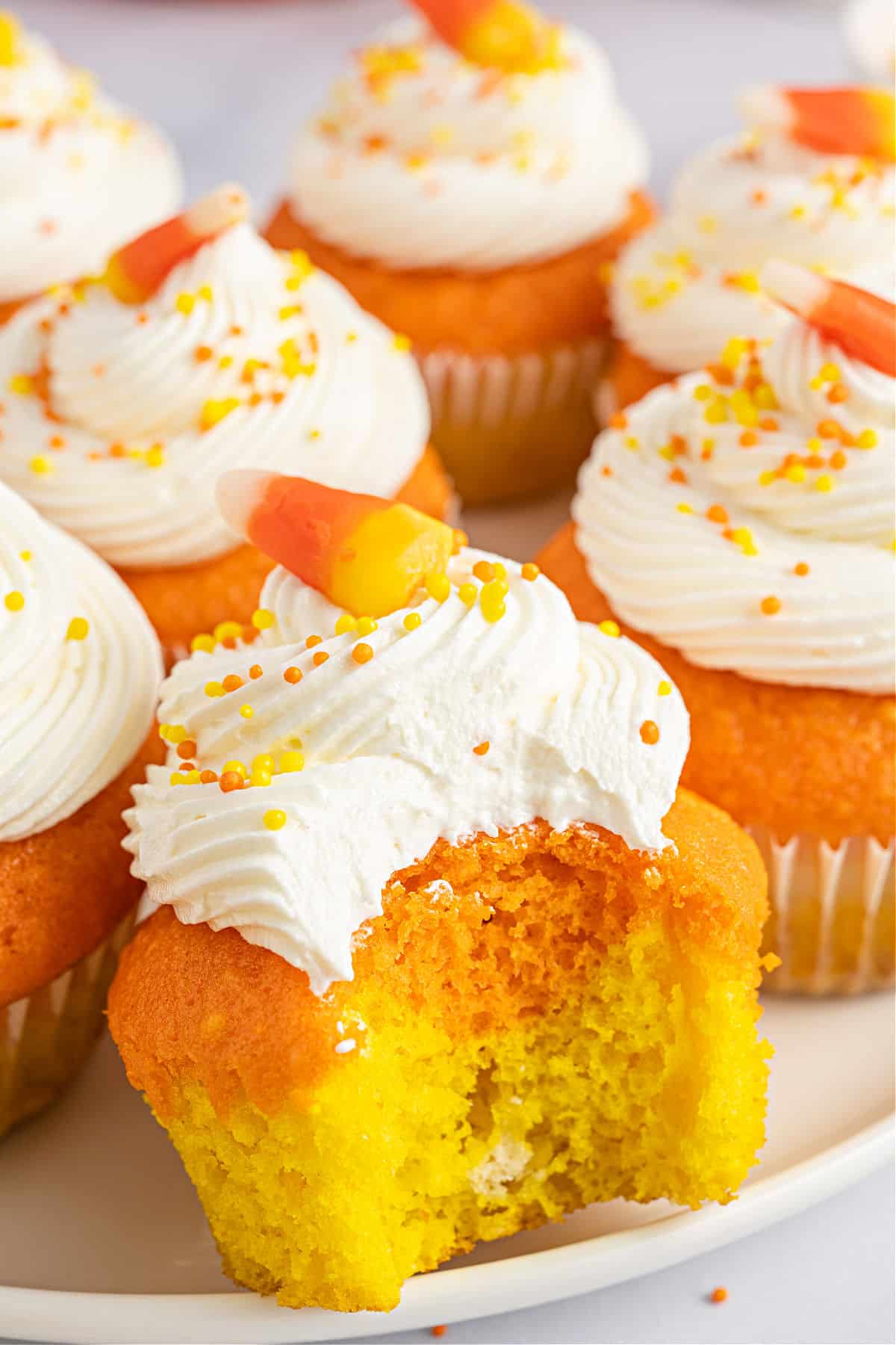 Candy corn colored cupcakes with frosting and bite taken out.