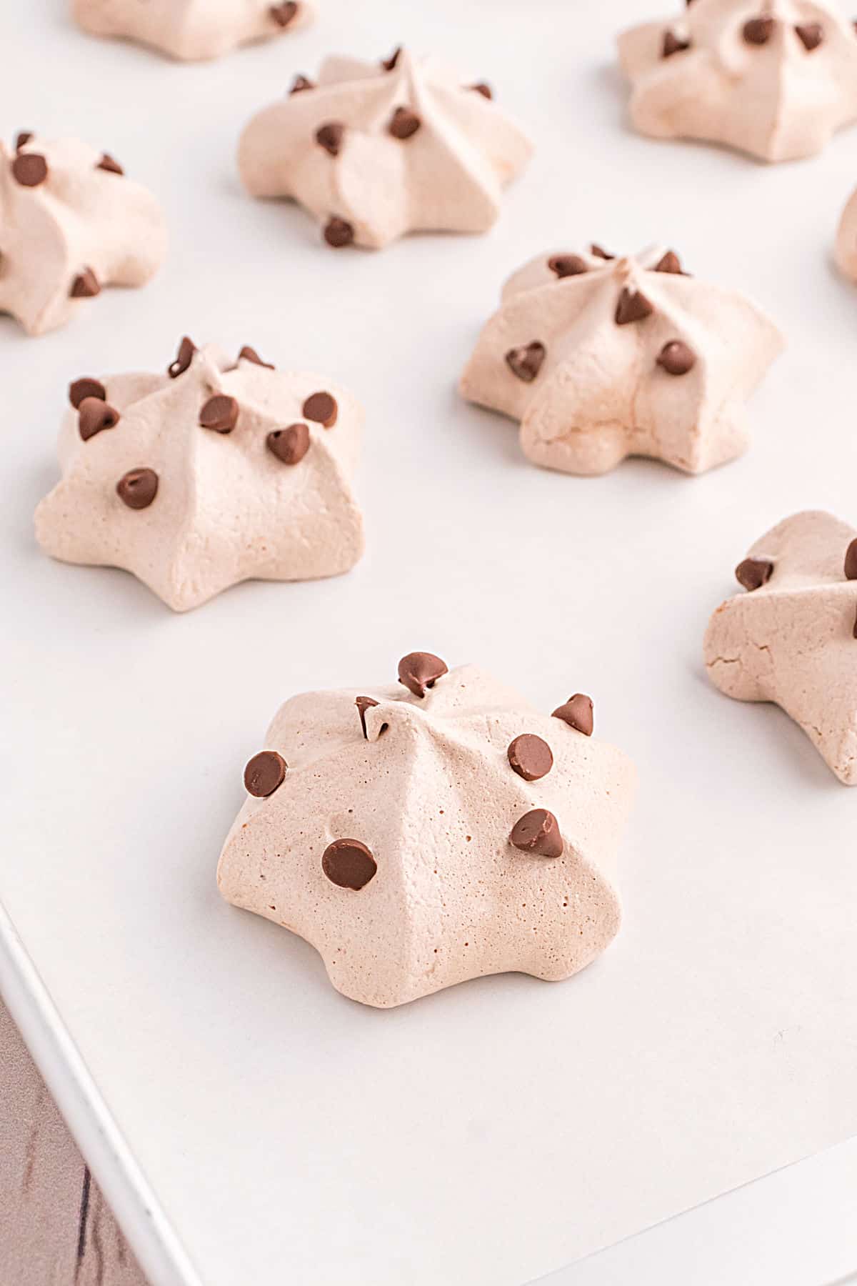 Chocolate chocolate chip meringue cookies on parchment paper.