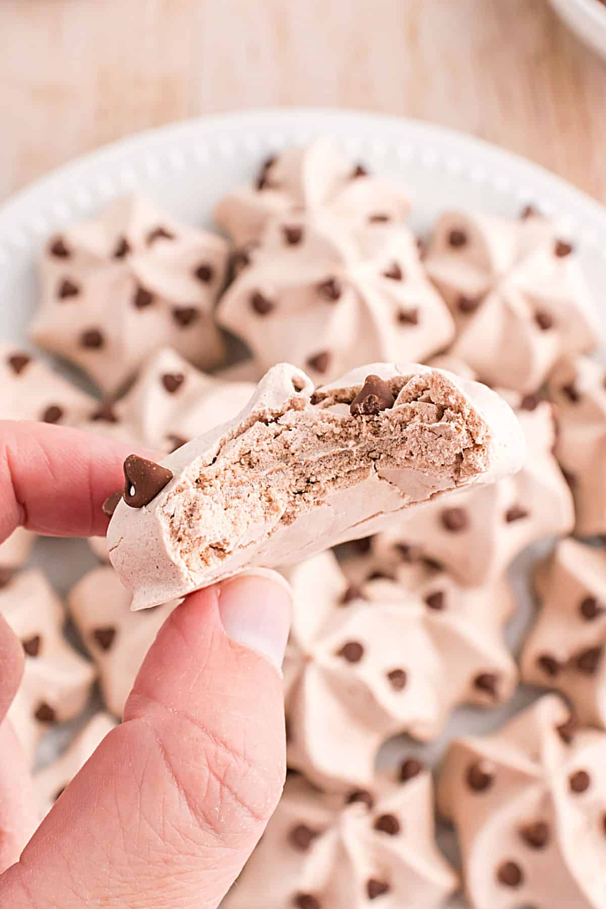 Chocolate meringue cookie with a bite taken out to show chewy texture.