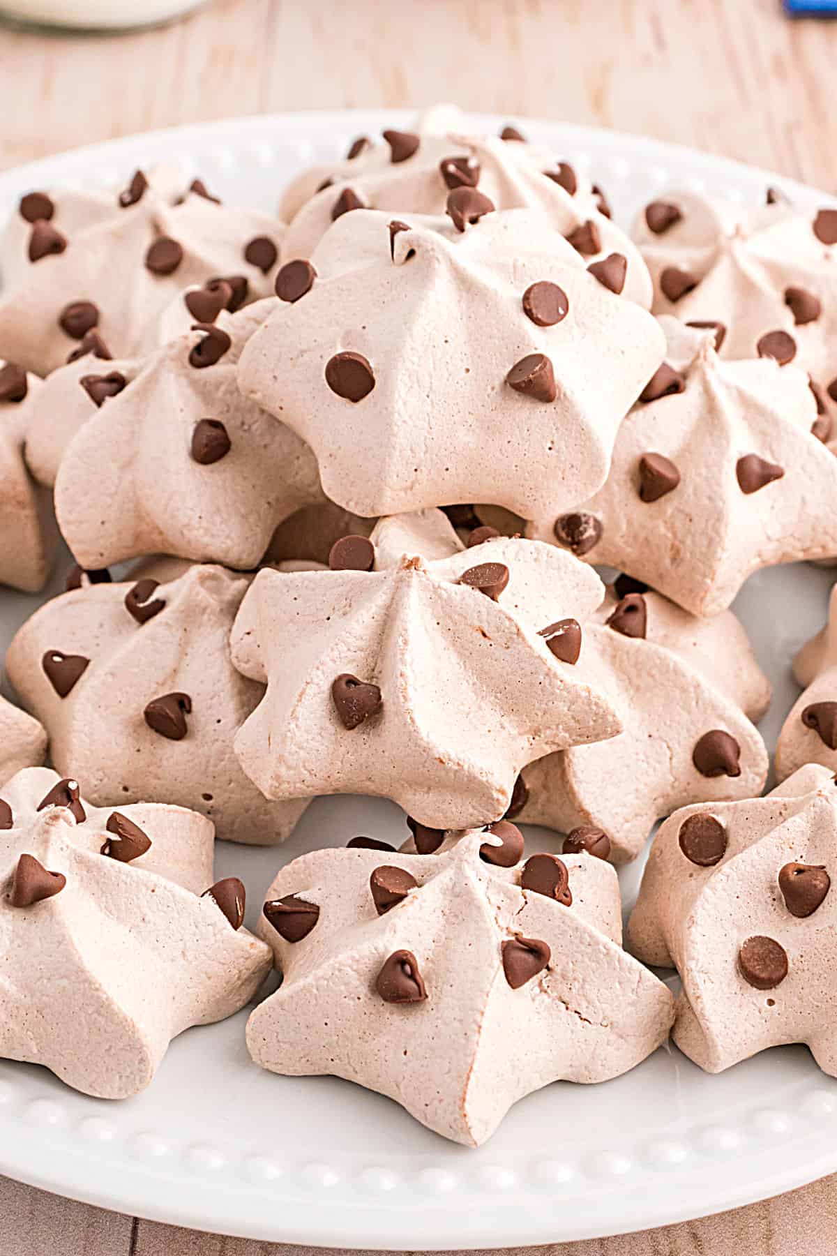 Chocolate chip meringue cookies stacked on a white serving plate.