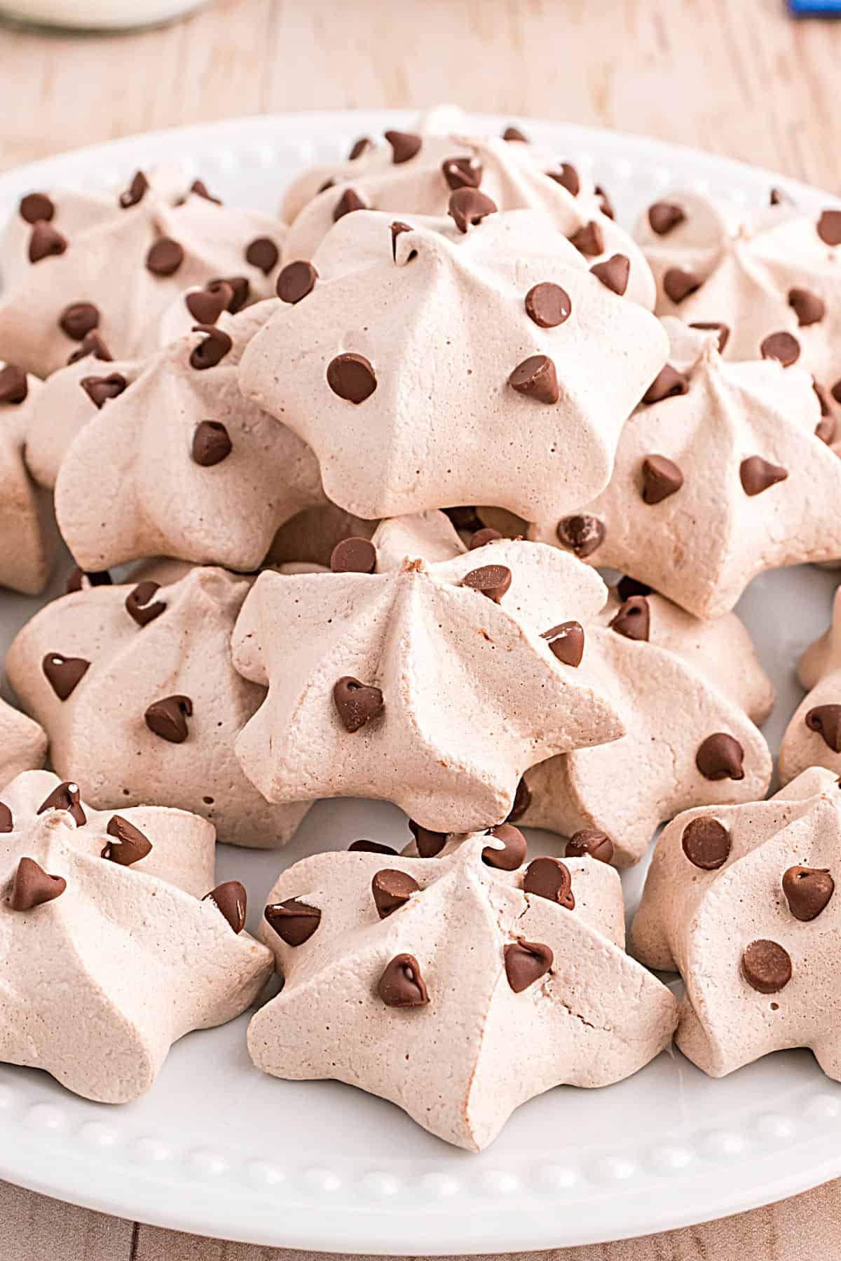 Chocolate chip meringue cookies stacked on a white serving plate.