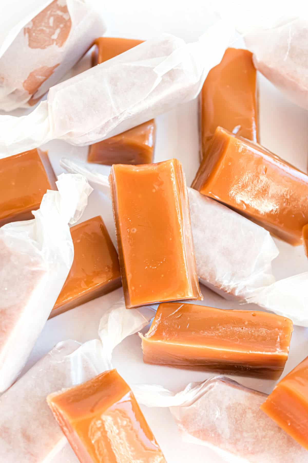 Homemade caramels wrapped in pieces of parchment paper.