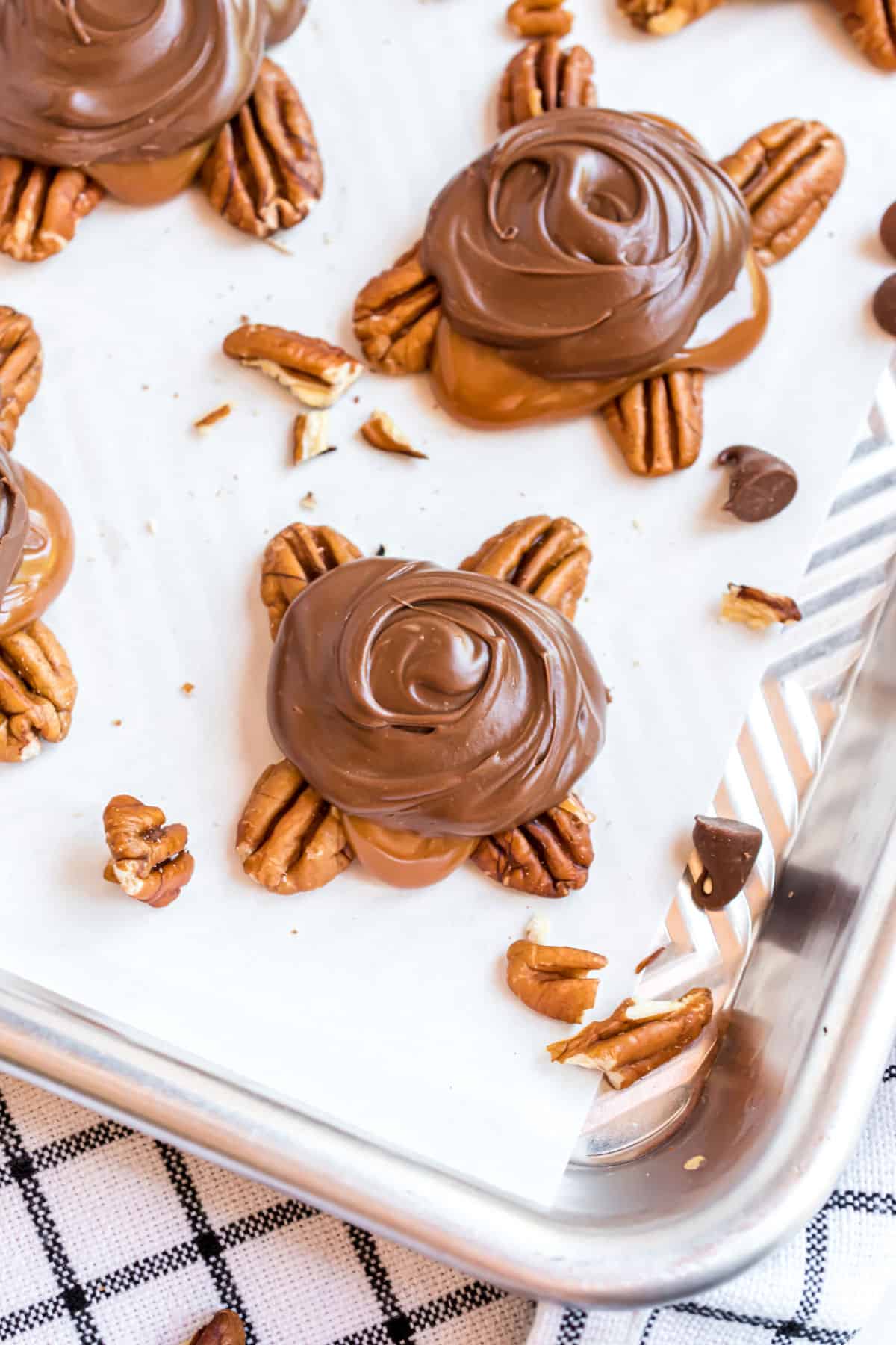 Homemade turtle candy on a parchment paper lined cookie sheet.