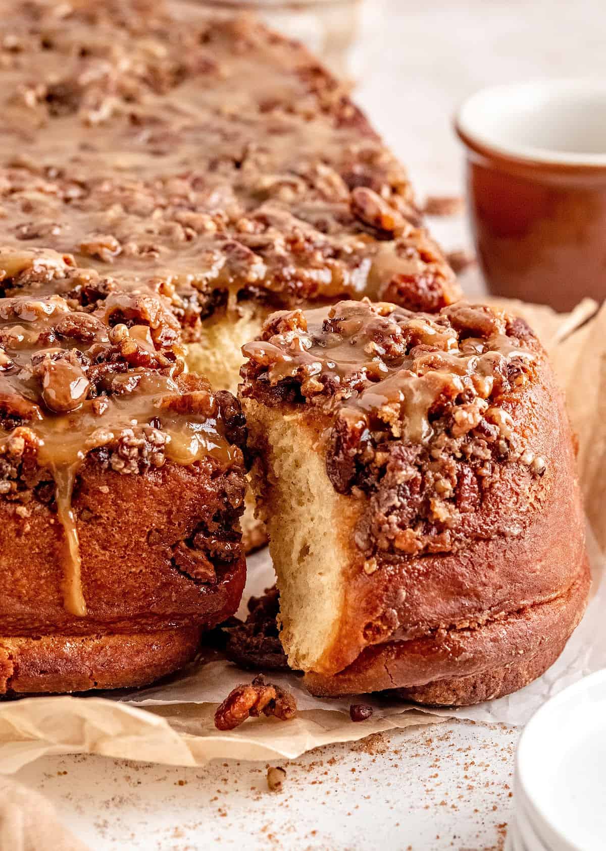 Pecan sticky buns on parchment paper with one roll being pulled out.