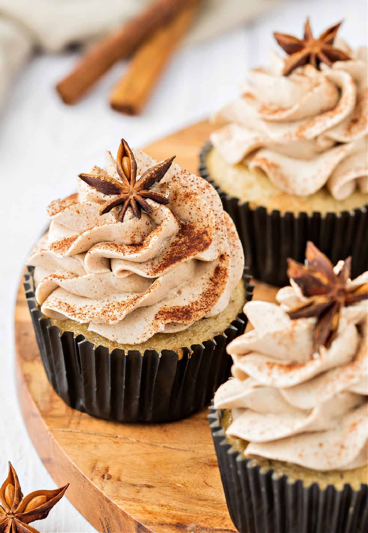Chai cupcakes on a wooden cake platter.