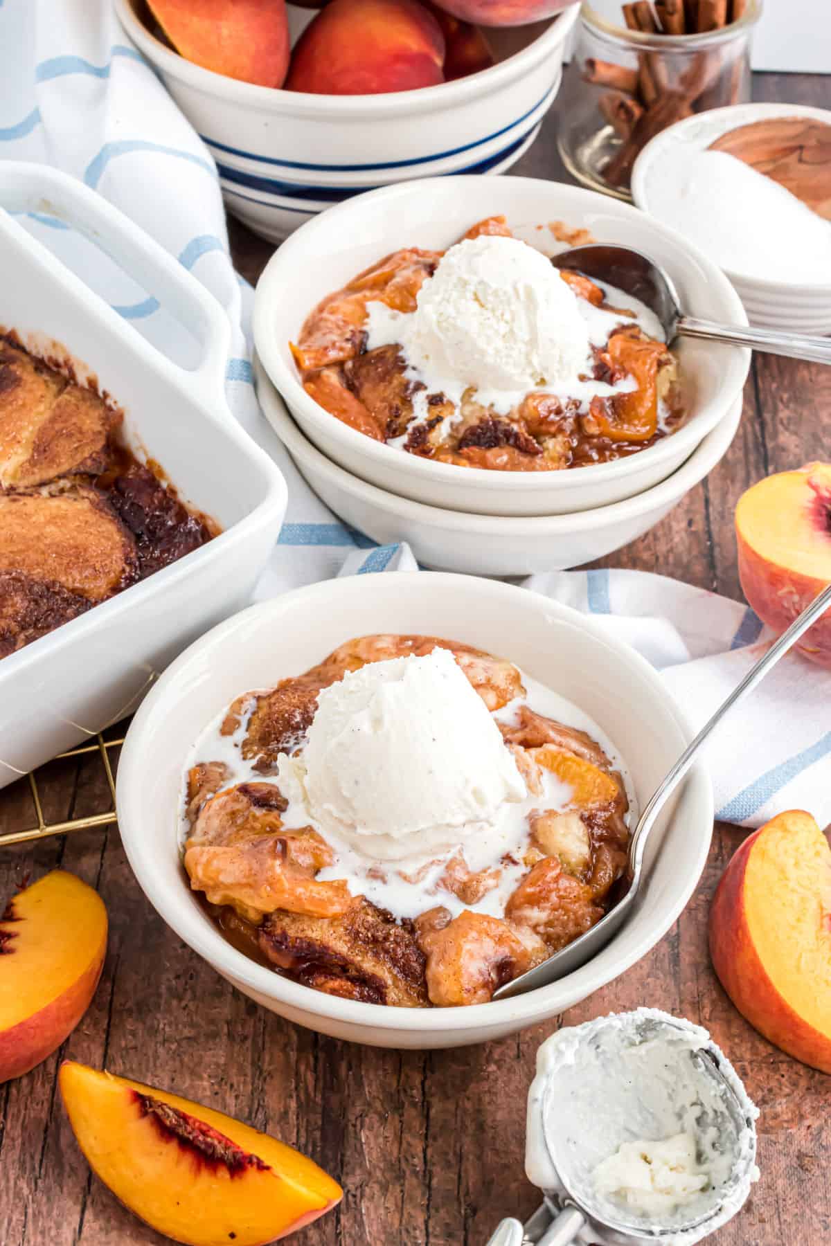 Peach cobbler served in white bowls with ice cream.