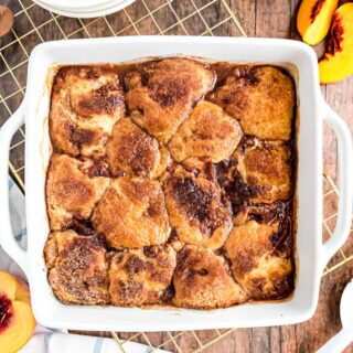 Peach cobbler baked in a square white baking dish.