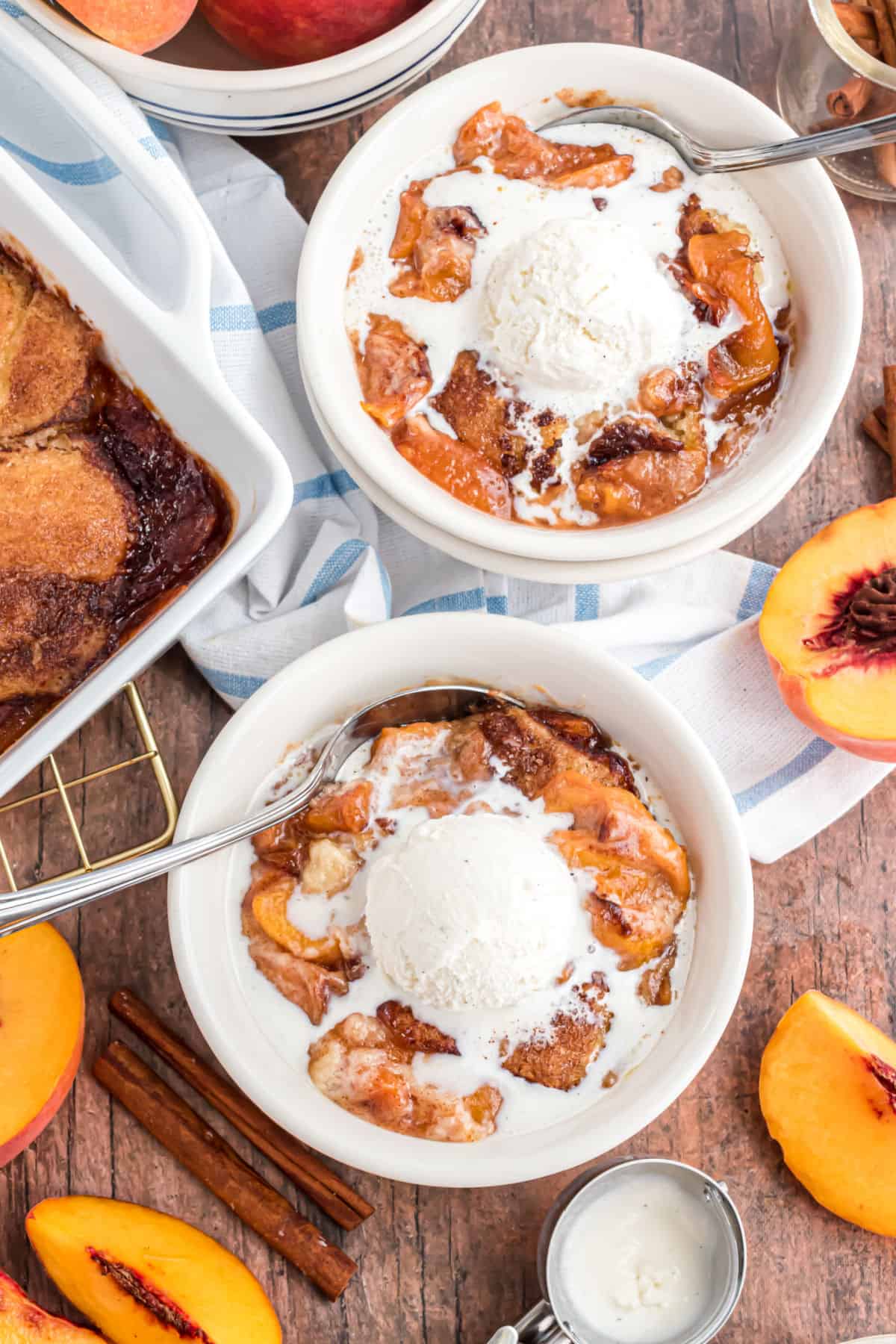 Peach cobbler with vanilla ice cream served in white bowls.