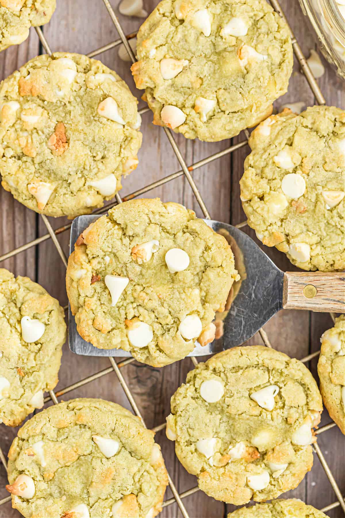 Pistachio cookies with white chocolate chips on a wire cooling rack.