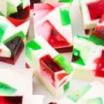 Colorful red, green, and white broken glass jello squares with a creamy white base, arranged closely together.