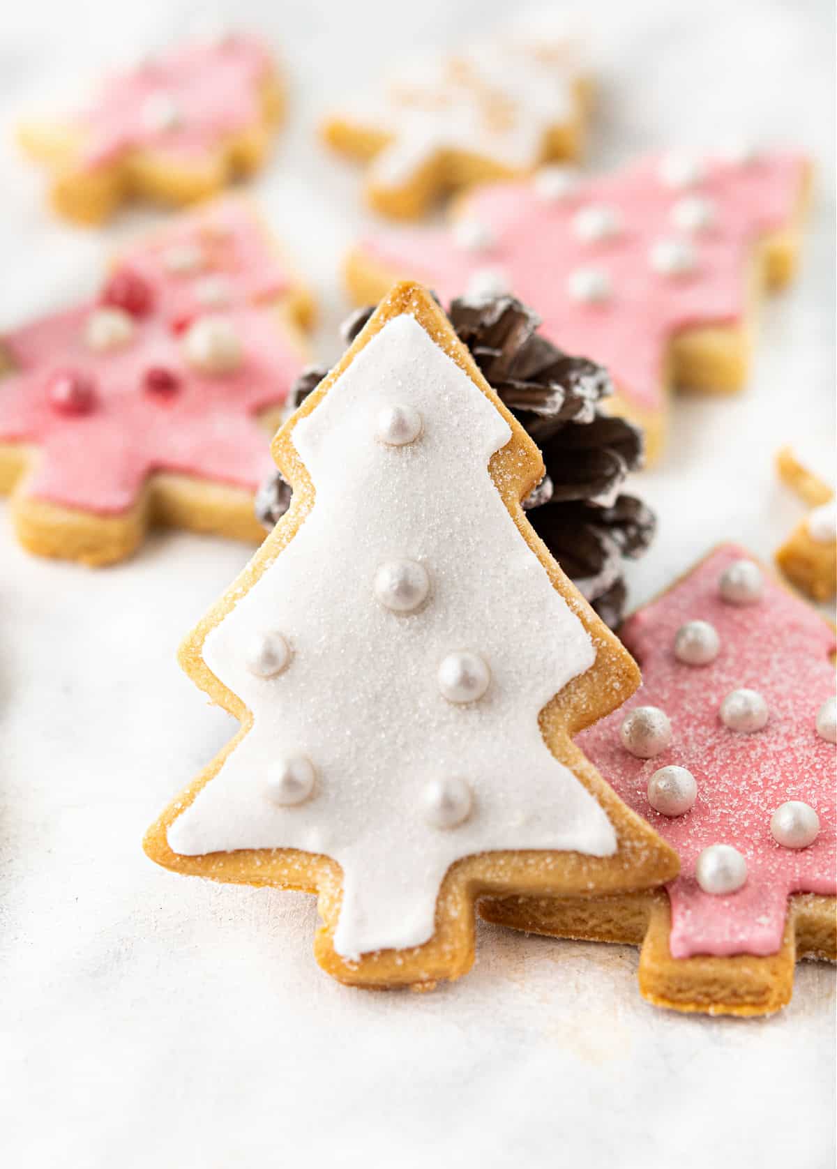 Christmas tree shaped cookies with pink and white royal icing.