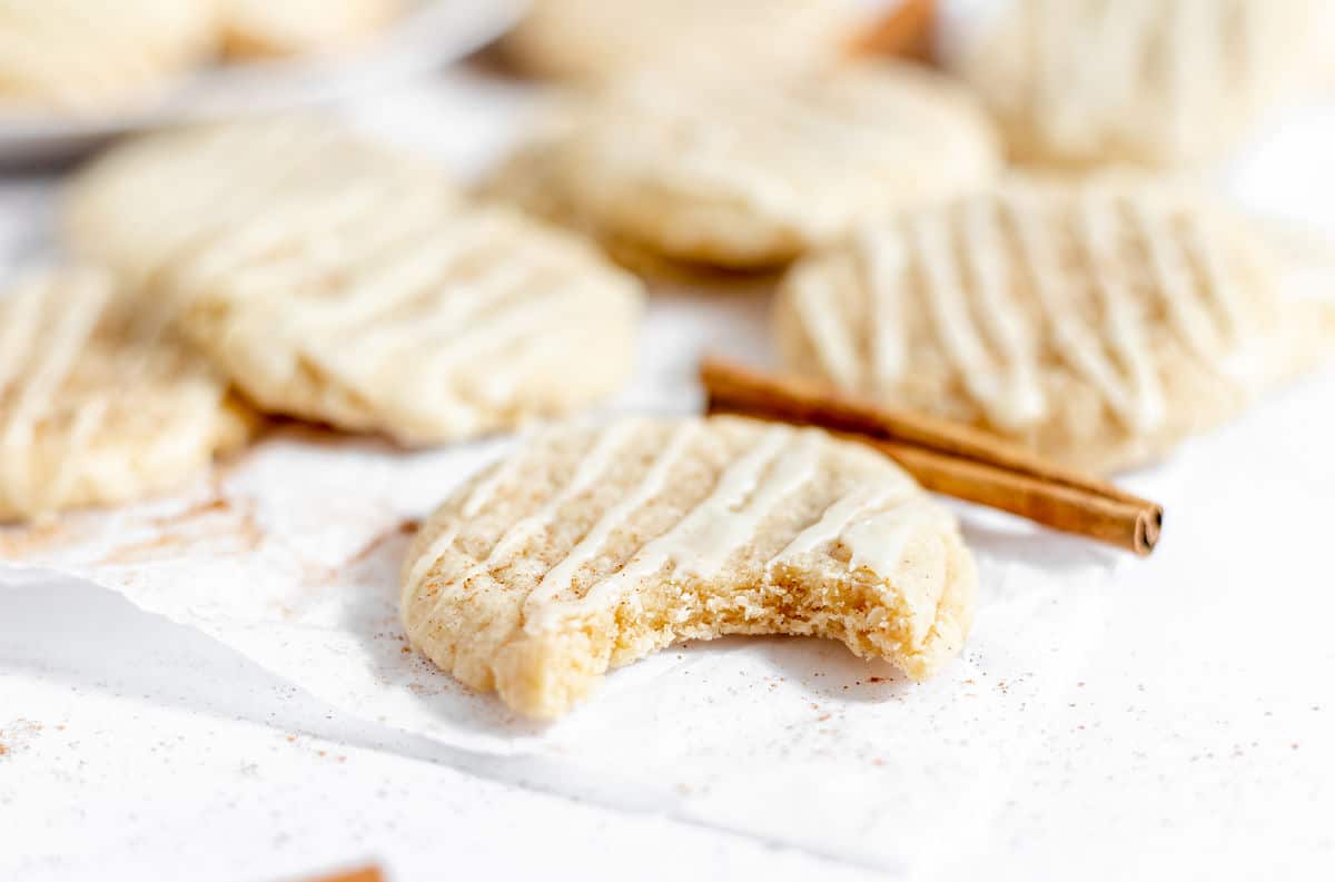 Eggnog cookies on parchment paper with a bite taken out of one cookie.