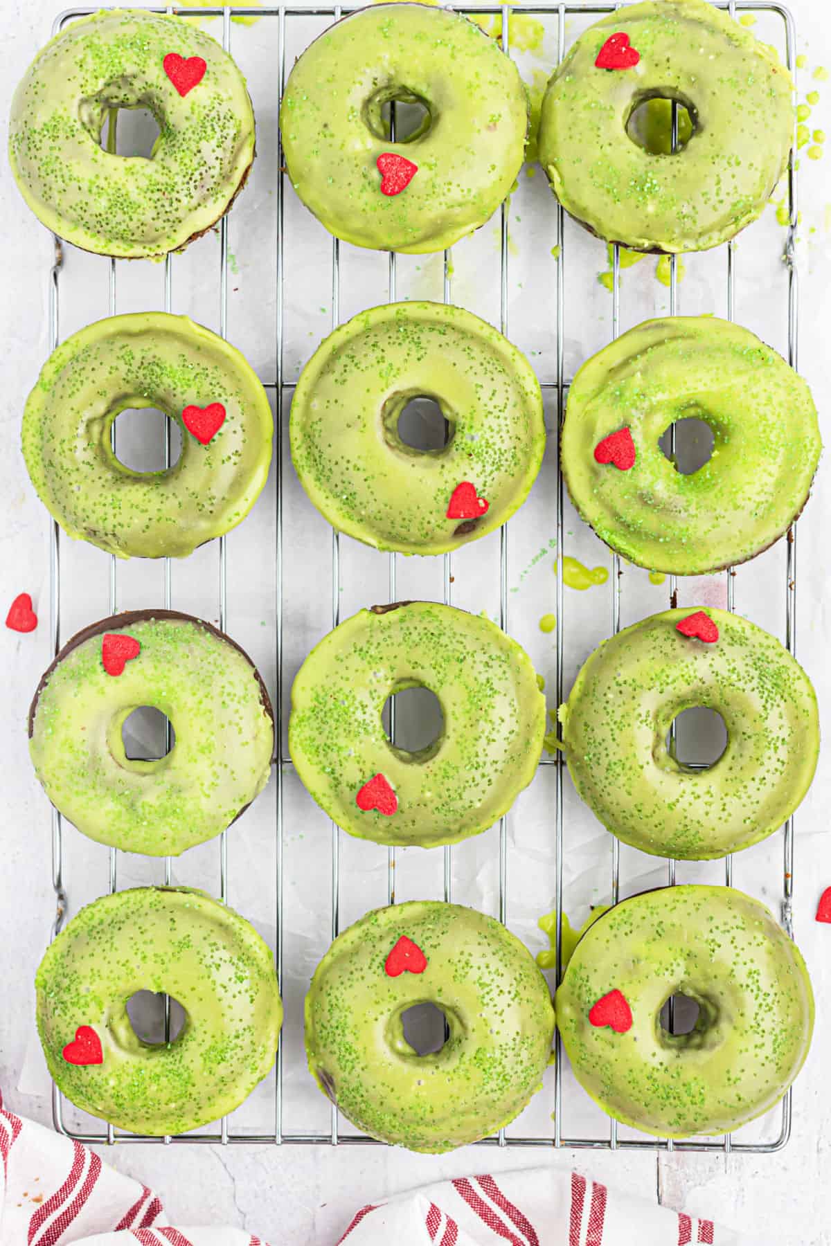 Grinch frosted donuts on a wire cooling rack.