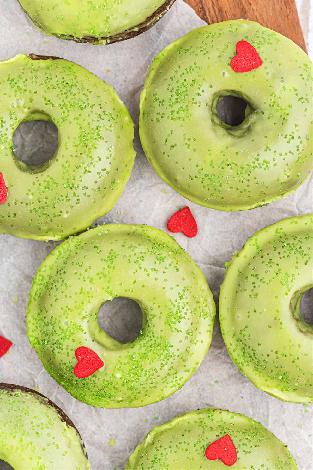 Green donuts with red heart sprinkles.