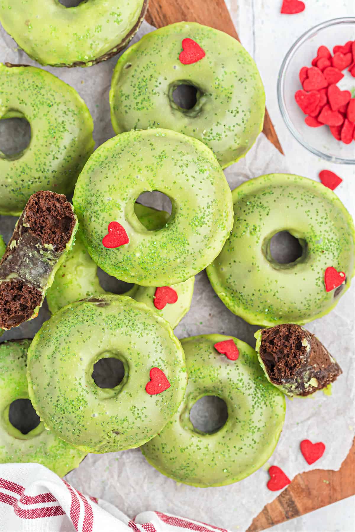 Chocolate donuts with green icing and red heart sprinkles.