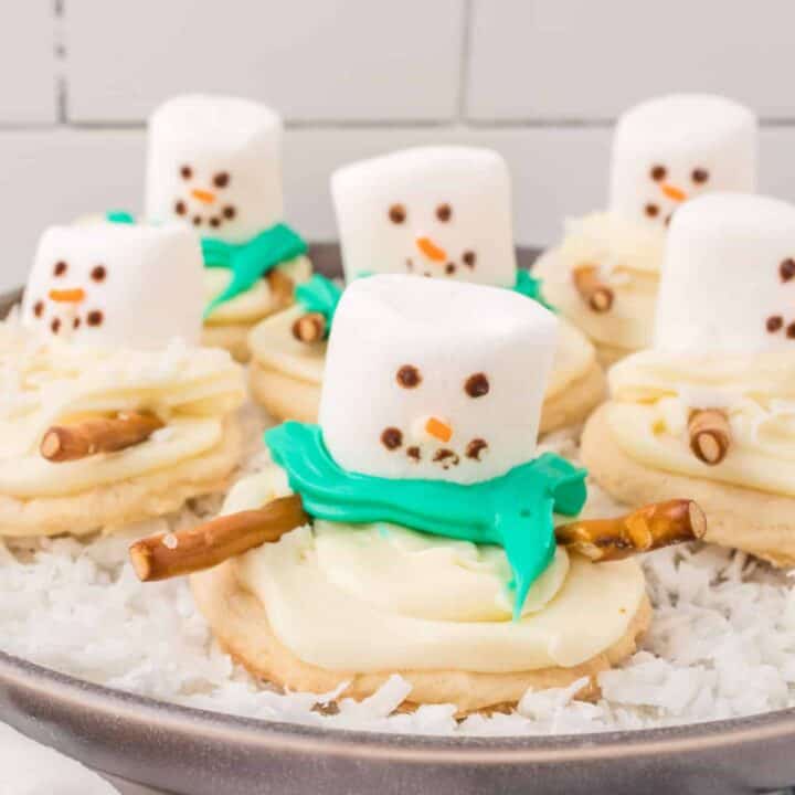 These adorable Melted Snowman Cookies will bring smiles to everyone's faces on a chilly day. A chewy sugar cookie base is topped with vanilla frosting and decorated to resemble a melted snowman for a fun winter treat!
