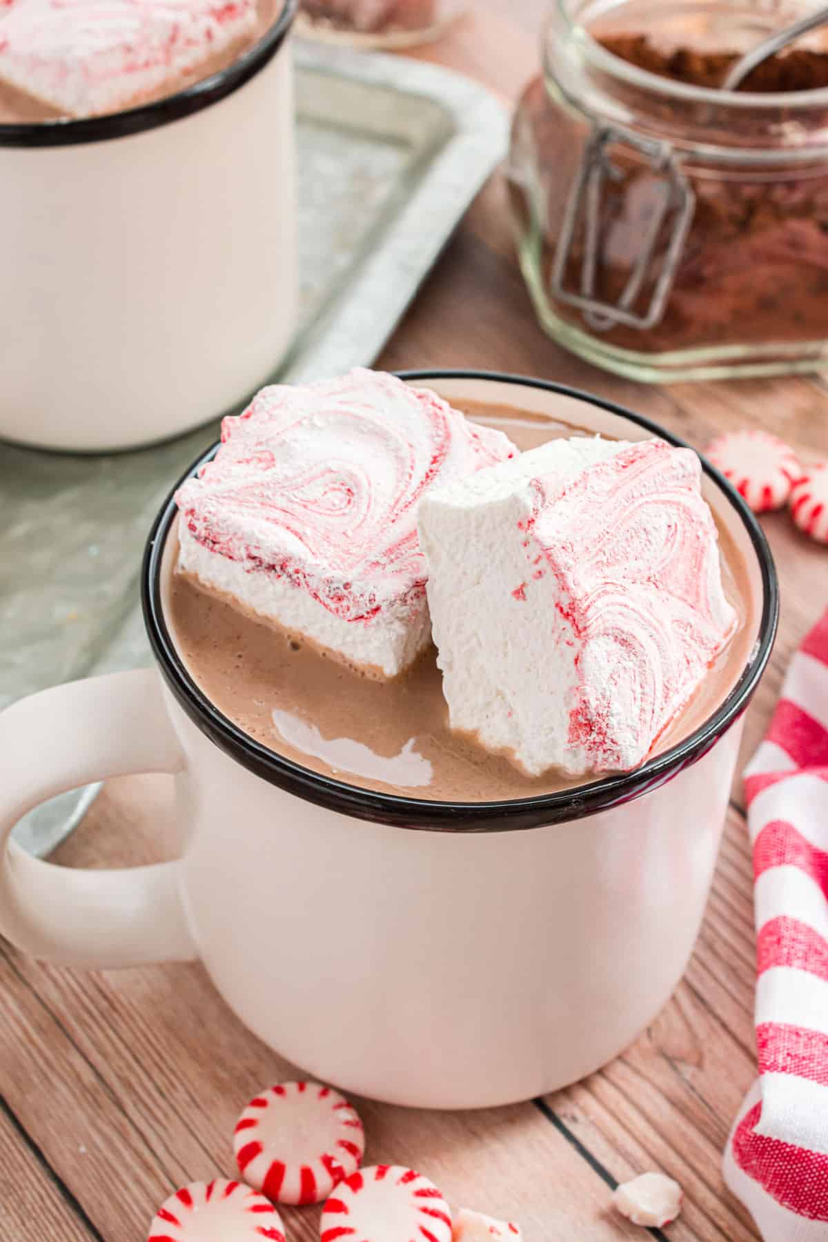 Two peppermint marshmallows in a white mug of hot cocoa.