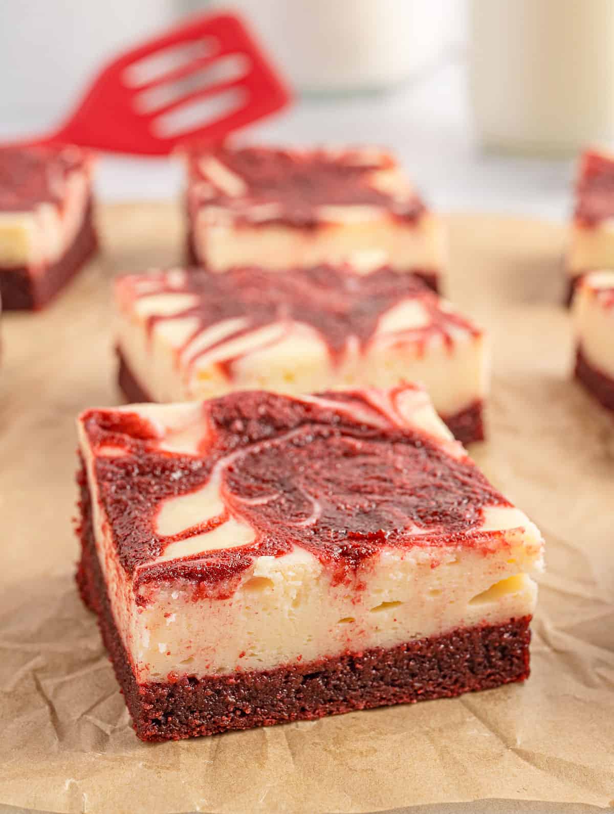 Red velvet brownies with a cheesecake layer on  parchment paper.